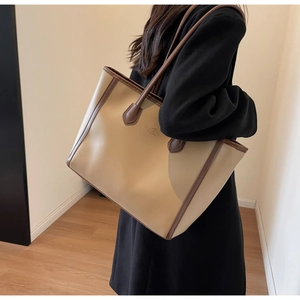 Detail view of khaki and brown tote bag with logo embossing and matte leather texture