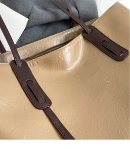 Close-up of khaki tote bag with pleated leather texture and dark brown zipper detail