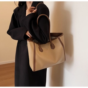 Brown tote bag shown on shoulder in a minimalist room with warm lighting