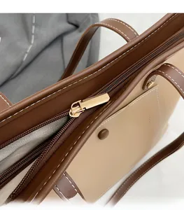 Detail of golden zipper and contrast stitching on a beige and brown tote bag