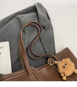 Close-up of brown faux leather tote bag showing white contrast stitching and shoulder strap