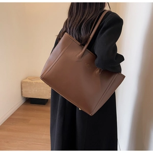 Detailed view of the brown leather tote bag showing fine texture and reinforced stitching