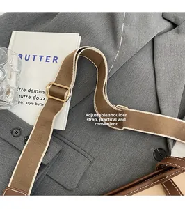 Close-up of adjustable canvas shoulder strap in brown and beige with gold metal buckle