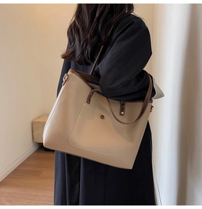 Detail view of large beige tote bag with brown straps and white contrast stitching