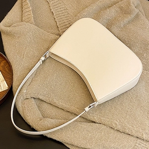 Creamy white leather crescent underarm bag with silver hardware on a knit sweater