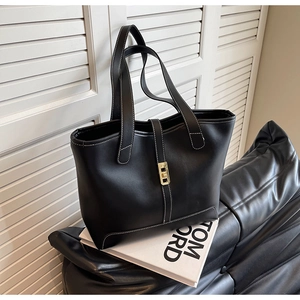 Close-up of black leather tote with white contrast stitching and gold metal twist lock