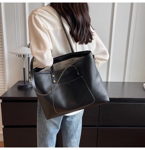 Close-up of black leather tote bag featuring white contrast stitching and magnetic front pocket