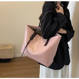 Close-up of pink leather tote bag with brown straps worn by model in a minimalist room