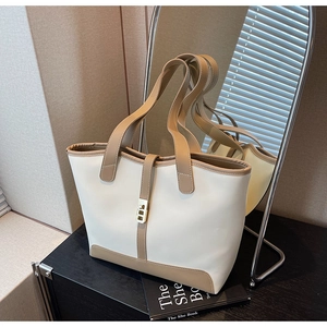 Detail view of contrast tote bag with metal buckle and dual straps on wooden desk