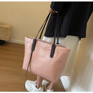 Detail of pink tote bag showing wrinkled leather texture and long brown handles