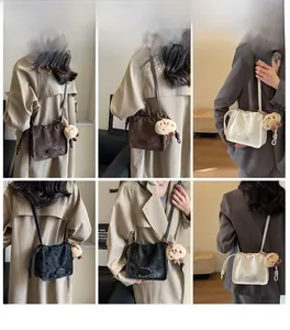 Model wearing bucket bags in brown, black, and white colors with drawstring detail