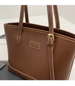 Détail du cabas en similicuir marron avec surpiqûres blanches et boucle dorée chic