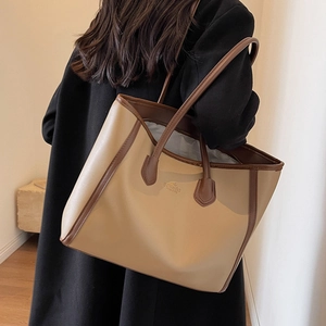 Brown and beige tote bag with long handles shown on model for a trendy autumn look