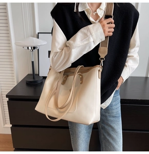 Detail view of cream tote bag with brown straps and detachable woven shoulder strap