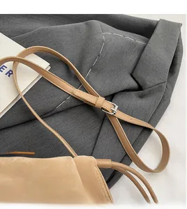 Detail of adjustable slim shoulder strap and silver buckle on beige leather crossbody bag