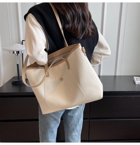 Detailed back view of a large two-tone tote bag worn by a model in a minimalist room