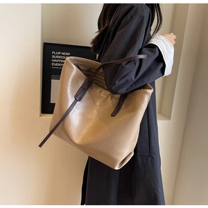 Detail of minimalist beige tote bag showing high-quality synthetic leather and brown handle