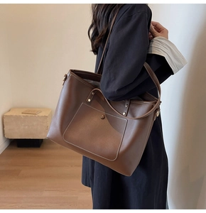 Detail of dark brown leather tote bag showing white contrast stitching and front pocket