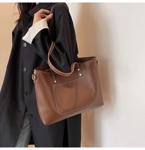 Close-up of brown faux leather tote bag featuring white contrast stitching and outer pocket