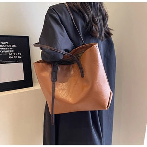 Detail of caramel leather tote bag with wrinkled texture and striped lining on shoulder