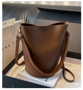 Detailed close-up of a brown bucket bag with golden hardware on a gift box