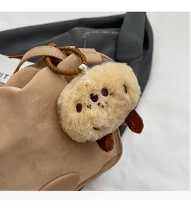 Detail of soft plush brown bag charm attached with a spiral cord to a handbag