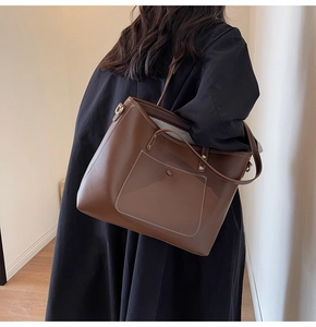 Brown leather tote bag showing large capacity and contrast stitching on a model