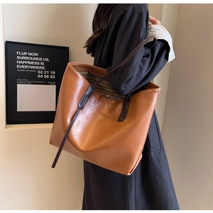 Brown leather tote bag showing large capacity and black and white striped lining detail