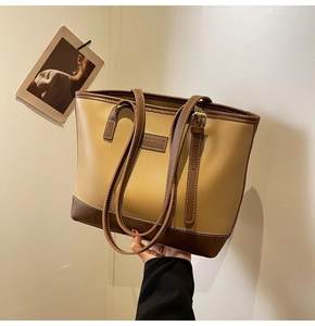 Détail du sac cabas bicolore avec écusson logo en cuir et double bandoulière réglable