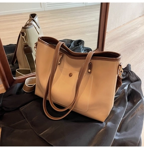 Detail view of a beige and brown tote bag showing the textured finish and buckle pocket