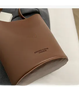 Close-up of the embossed logo on the premium dark brown leather bucket bag material