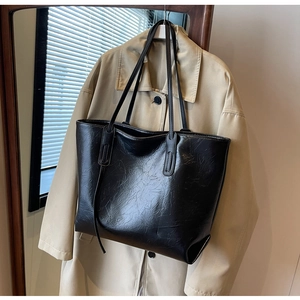 Macro view of minimalist black tote bag with polished crinkled leather texture detail