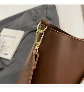 Macro shot of dark brown leather handbag featuring gold polished metal hardware and stitching