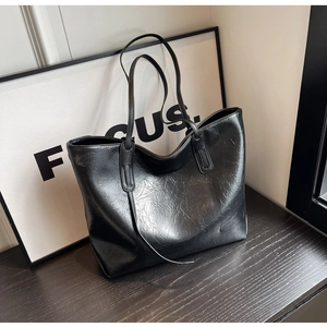 Detailed view of large black tote bag featuring vintage wrinkled texture and long straps
