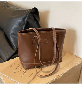 Détail du sac cabas en cuir marron vintage avec coutures contrastées et patch logo