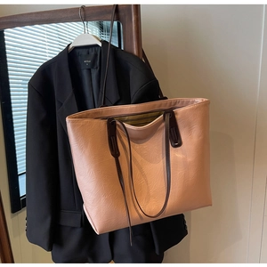 Detailed view of large tote bag featuring textured crinkled leather and slim brown straps