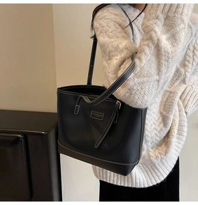 Détail du sac cabas noir avec surpiqûres contrastées blanches et plaque de logo mode