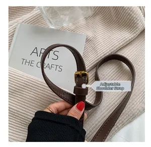 Close-up of adjustable dark brown leather shoulder strap with vintage metal buckle details