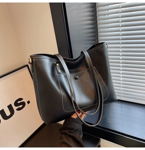 Detail of black tote bag with white contrast stitching and functional front pocket