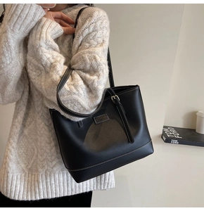 Détail du fourre-tout noir avec surpiqûres contrastées blanches et plaque de logo