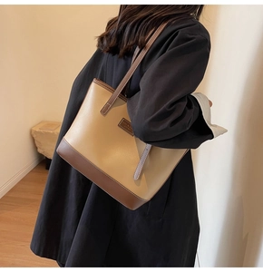 Détail d'un grand sac cabas bicolore avec bandoulière en cuir porté par un mannequin