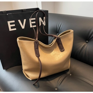 Detail of beige tote bag with crinkled leather texture on a stylish black sofa