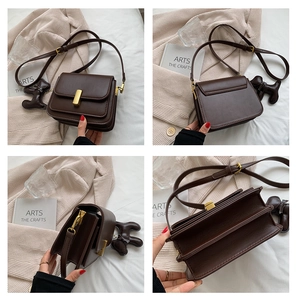 Detail view of dark brown retro crossbody bag with gold lock and dog charm accessory