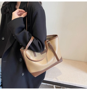 Détail d'un sac cabas bicolore montrant la texture du cuir PU et les boucles métalliques