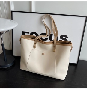 Detail of a minimalist cream tote bag with brown straps and a golden magnetic clasp closure