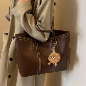Brown leather tote bag with contrast stitching and plush charm for women