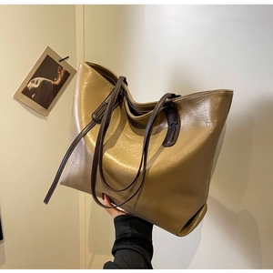 Close-up of khaki tote bag with textured patent leather and dark brown handles