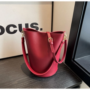 Detail view of burgundy leather bucket bag with adjustable strap and gold metal hardware