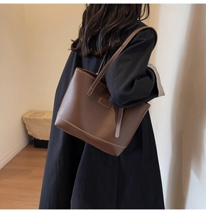 Gros plan du sac cabas en cuir marron foncé avec surpiqûres blanches et étiquette minimaliste