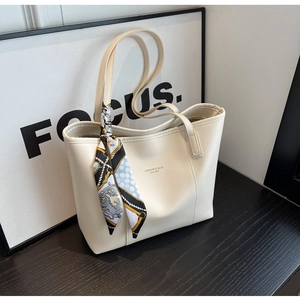 Detail view of large beige tote bag with chic decorative silk scarf and leather logo